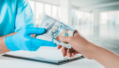A person handing a plastic surgeon $100 bills.