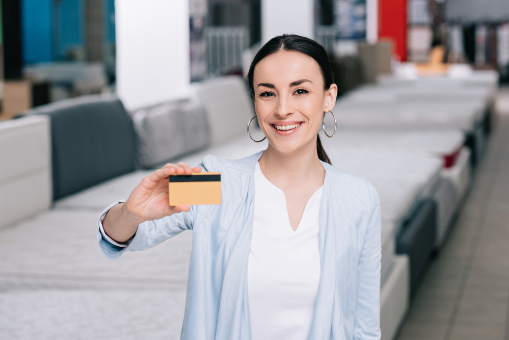 A person standing in a store, holding a credit card for the camera.