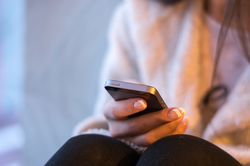 A person checks their phone on a couch.