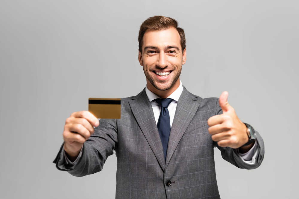 A professional holding up a credit card and giving a thumbs up.