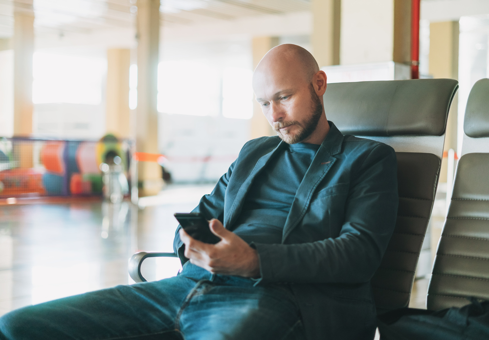 A person sits in a chair, using their phone.