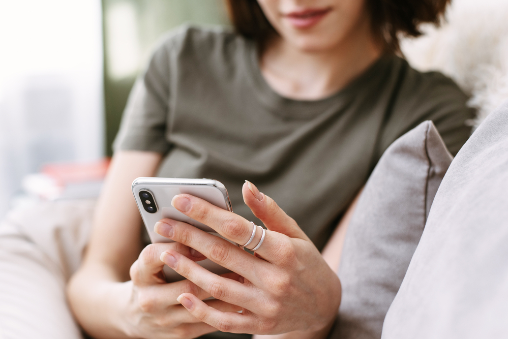 A person laying on their couch, checking their phone.