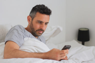 A person checking their credit score on their phone while in bed.