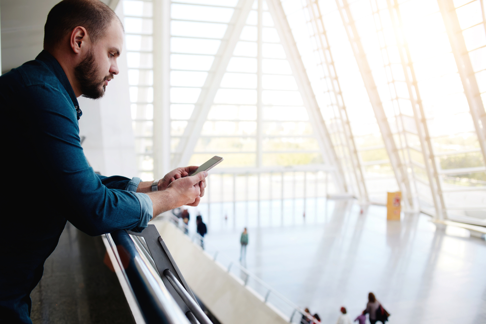 A person checking their phone in a public transit station.