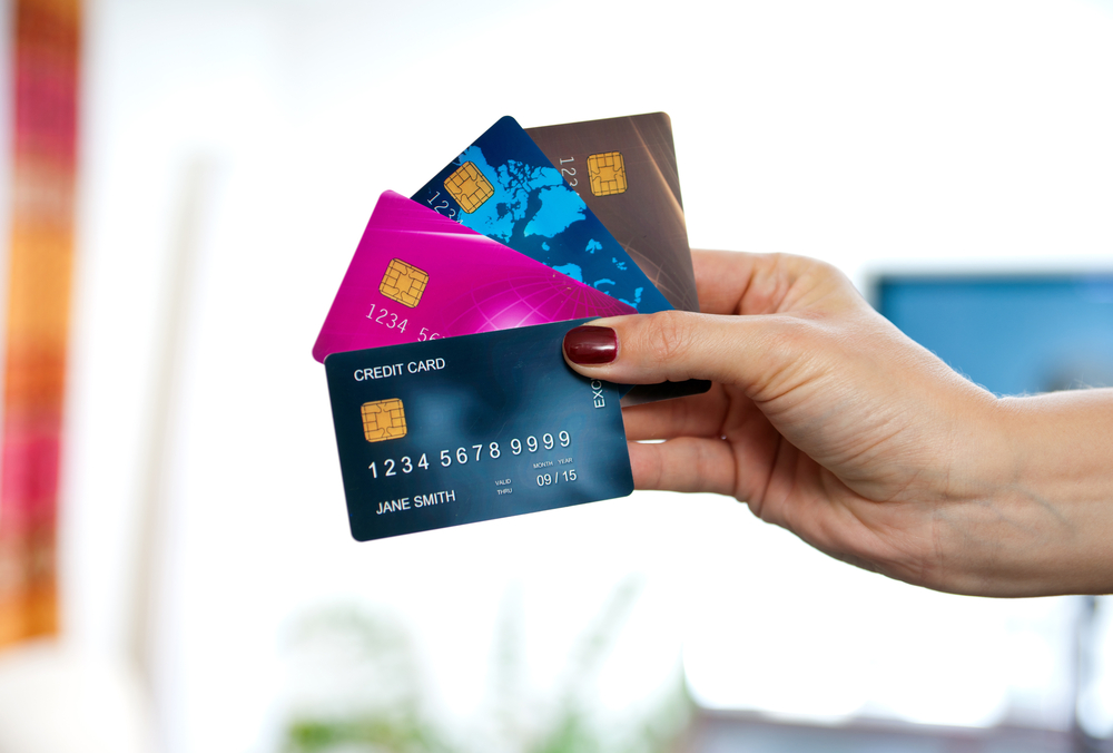 A person's hand holds several, fanned out credit cards.