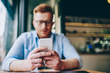 A closeup shot puts a person's hands into selective focus, as they type on a phone.