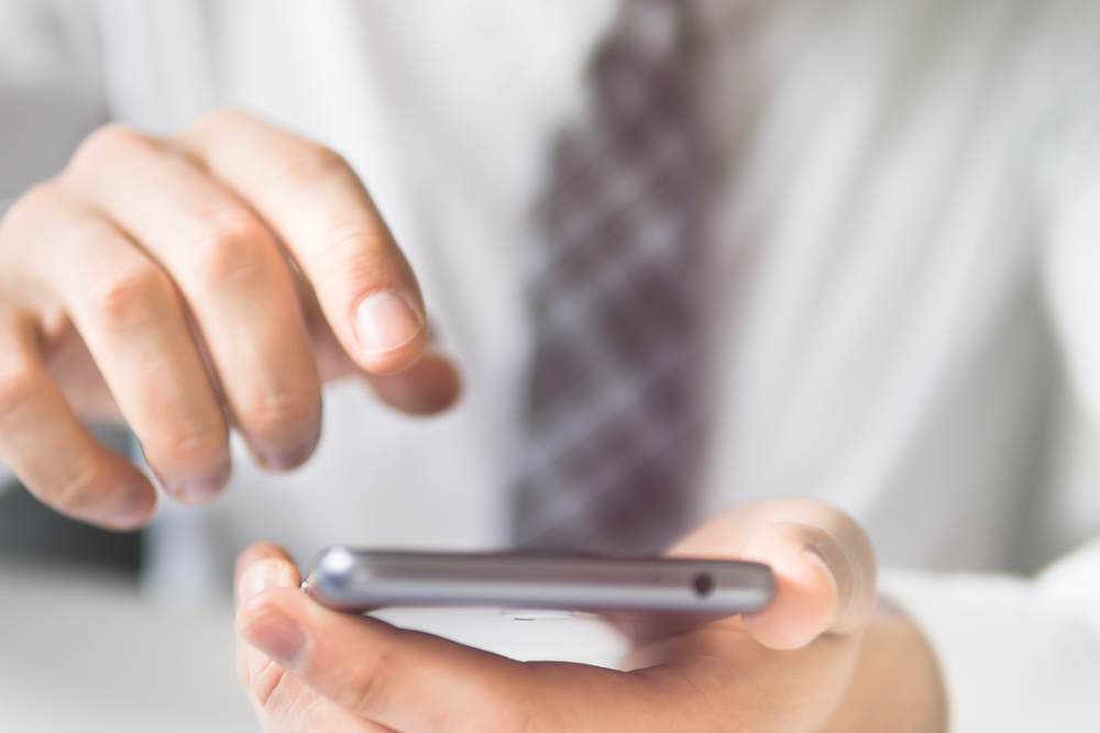 A person wearing nice clothes checks their phone.