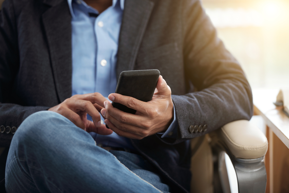 A person sitting in a chair, checking their phone.