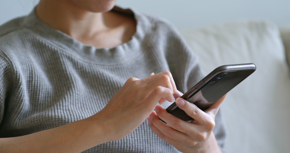 A person sitting down, using their phone.