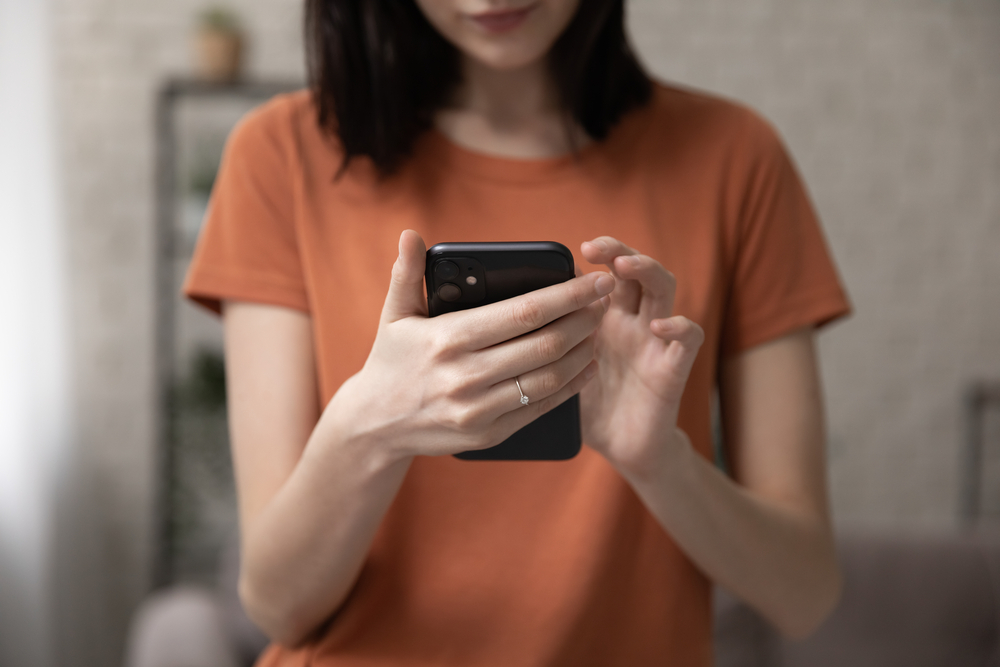 A person standing up while using their phone.