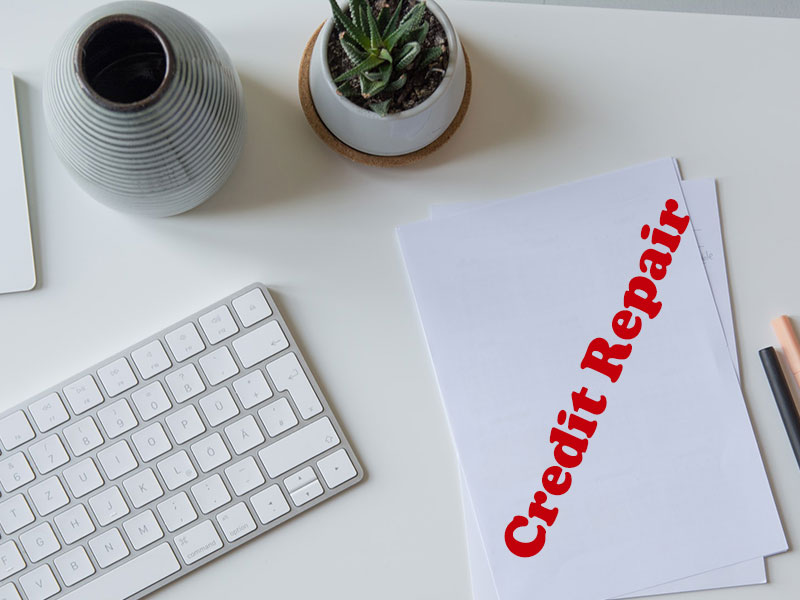 white paper with credit repair text on it beside white apple keyboard