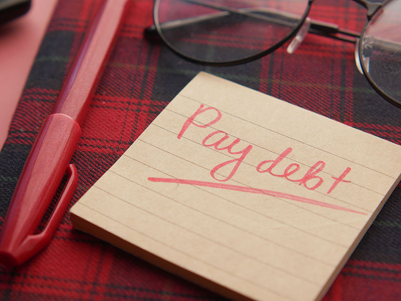 the word pay debt on a paper
