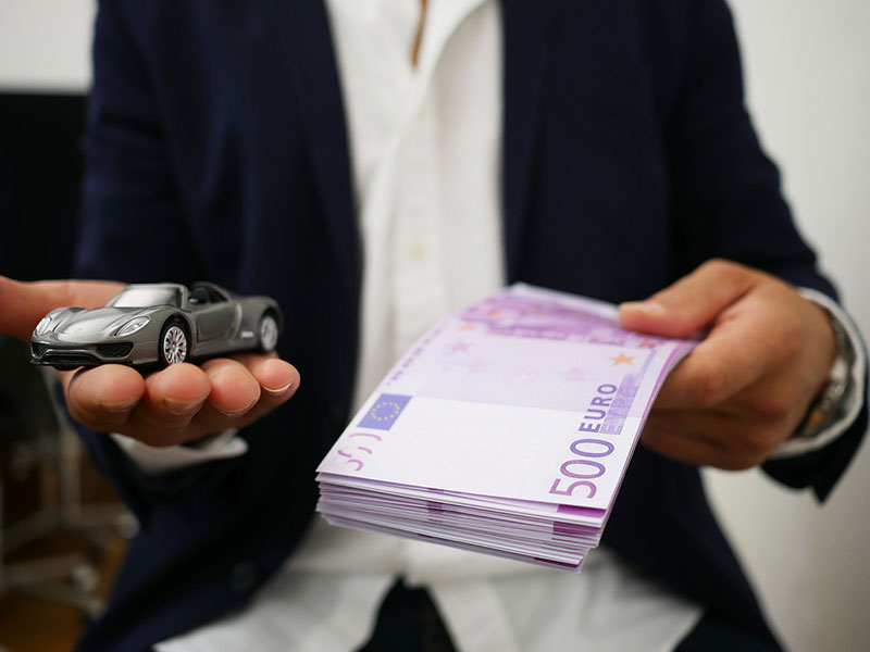 man holding toy car and money in his hands